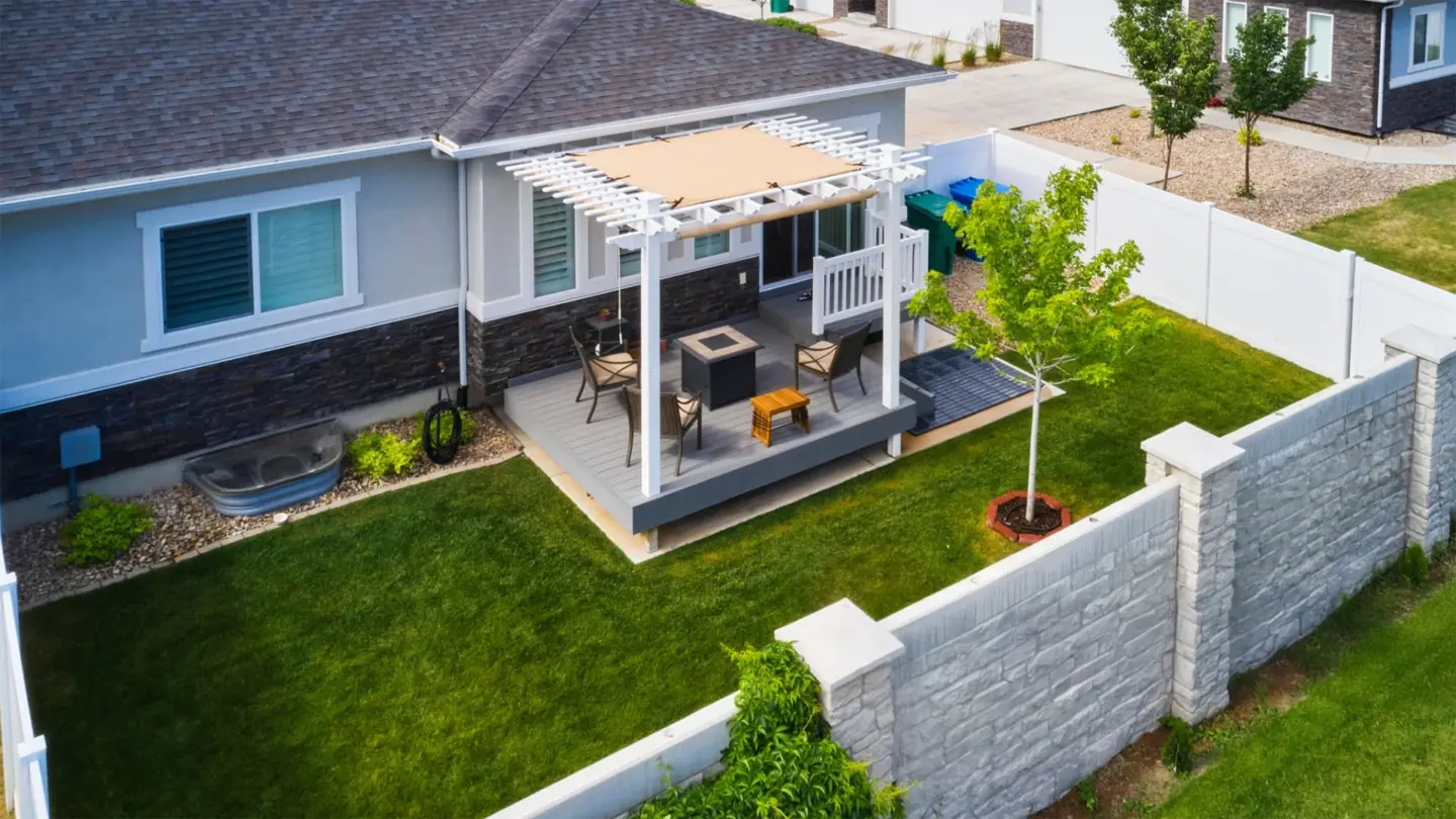 aerial-view-of-the-custom-residential-deck-with-pergola-and-white-railings-and-outdoor-living-fire-place-on-the-backyard-with-white-vinyl-and-brick-wall-fence-in-southern-maryland