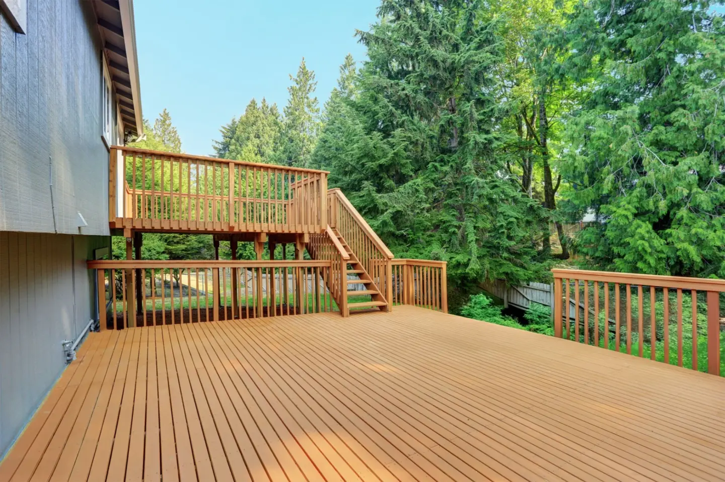 backyard-view-of-composite-grey-rambler-house-with-upper-and-lower-decks-with-trees-on-the-background-in-southern-maryland