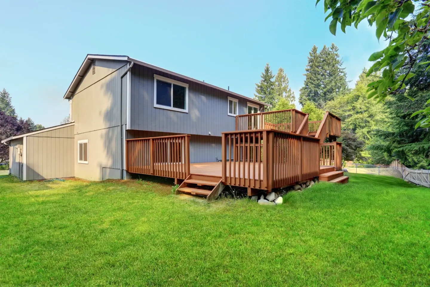 backyard-view-of-wooden-upper-and-lower-decks-attached-on-the-gray-residential-house-with-overlooking-view-in-southern-maryland