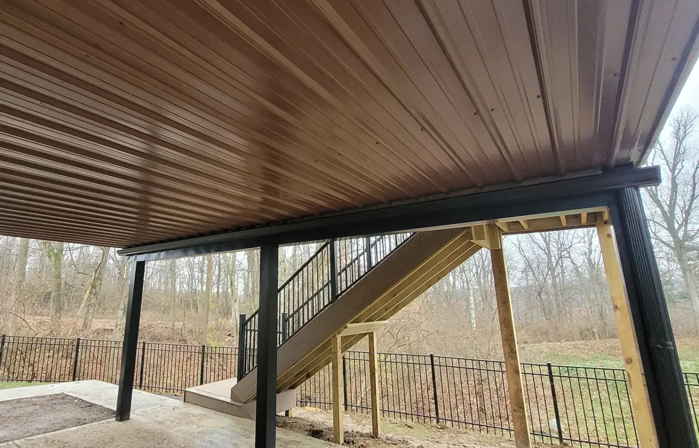 deck-frame-structural-on-the-raised-deck-with-black-metal-railing-and-black-metal-privacy-fence-featuring-dry-trees-and-cloudy-sky-on-the-background-in-southern-maryland