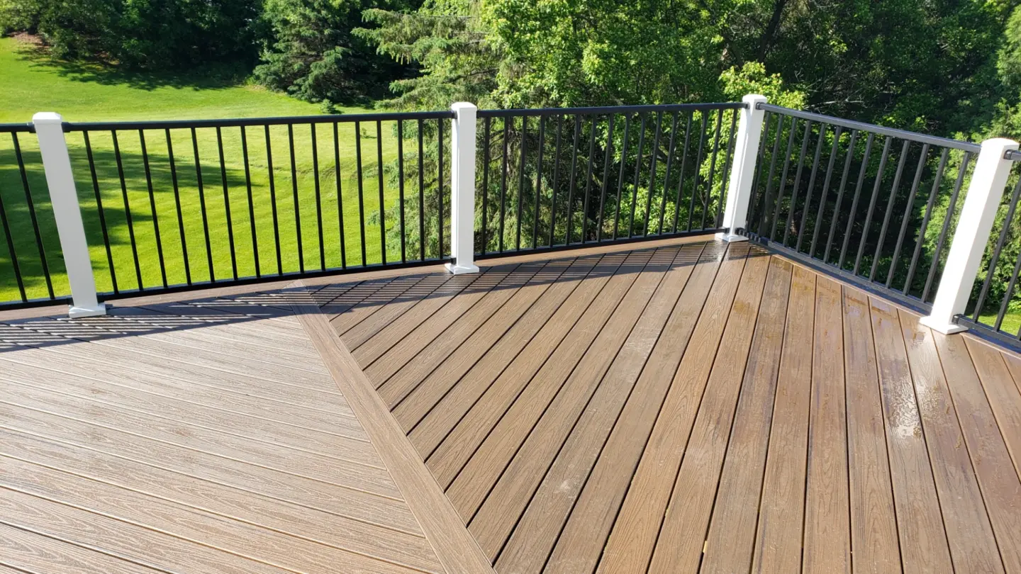 elevated-composite-newly-cleaned-deck-with-black-metal-railing-and-contrasting-board-pattern-surrounded-by-trees-and-grass-on-the-background-in-southern-maryland