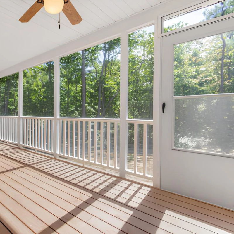 interior-of-the-screened-in-porch-with-white-railings-and-a-fan-on-the-white-ceiling-featuring-beautiful-trees-on-the-background-in-southern-maryland