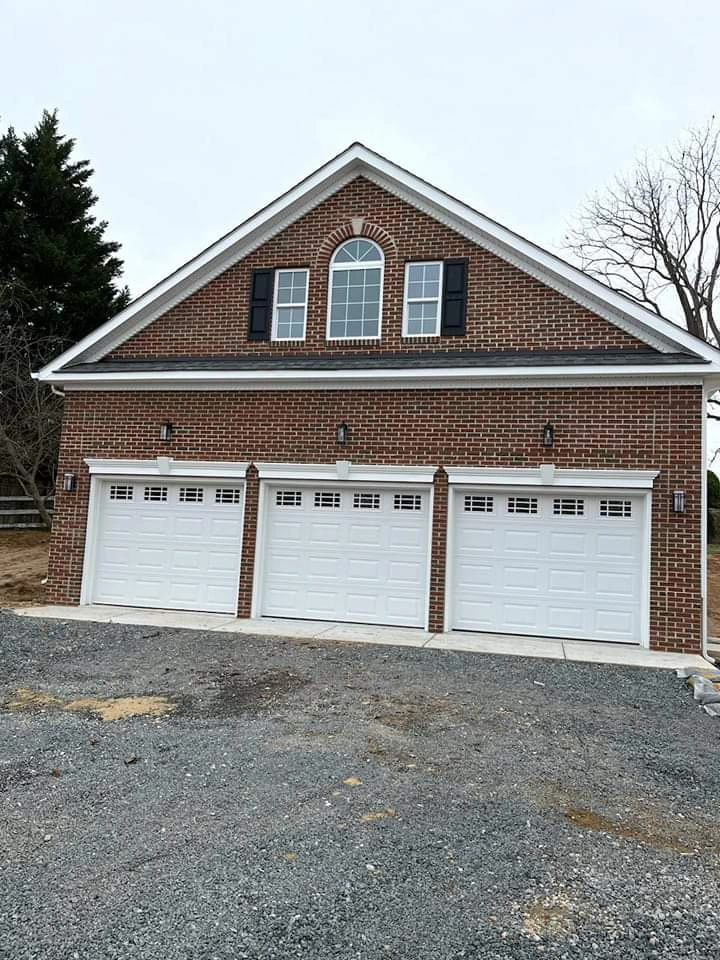 new-roof-installation-on-the-brick-house-with-three-white-garage-door-in-cloudy-sky-area-in-huntingtown-maryland