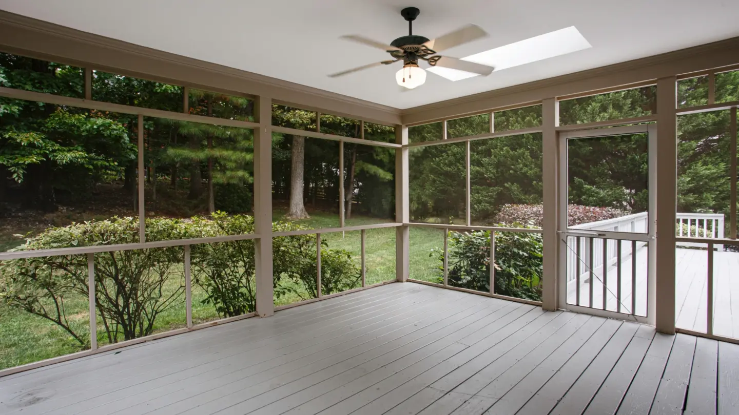 screened-in-porch-attached-to-house-with-gray-deck-and-a-fan-on-the-ceiling-with-nature-view-on-the-background-in-southern-maryland